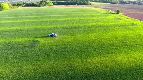 Tractor Sprays Verdant Field from Aerial Perspective