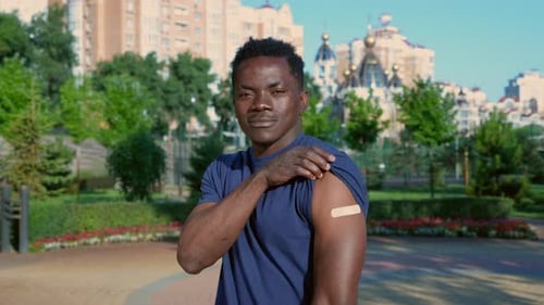 Smiling Man Shows Arm After Vaccination in Park