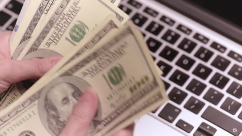 Hands Count US Dollars Over Laptop Keyboard