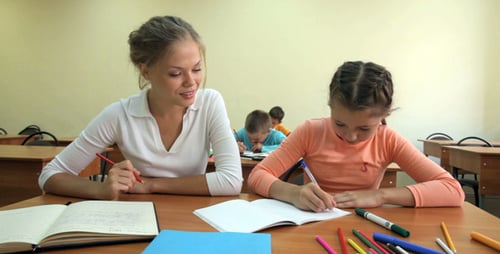 Teacher Helping Student with Classwork in Classroom