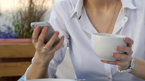 Woman Hand Using a Smart Phone During Breakfast In Cafe With Coffee