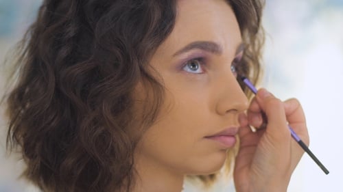 Professioneller Maskenbildner, der für ein Fotoshooting ein schönes junges Gesicht schminkt