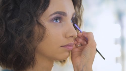 Professional Makeup Artist Applying Make Up On a Beautiful Young Face For a Photoshoot