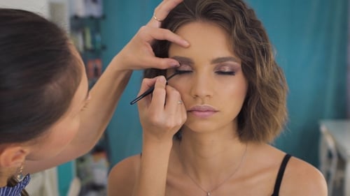 Woman Getting Eyeliner Applied by Makeup Artist