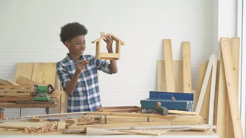 Enfant charpentier afro-américain souriant heureux de travailler avec du bois et du papier abrasif, d'étudier, d'apprendre