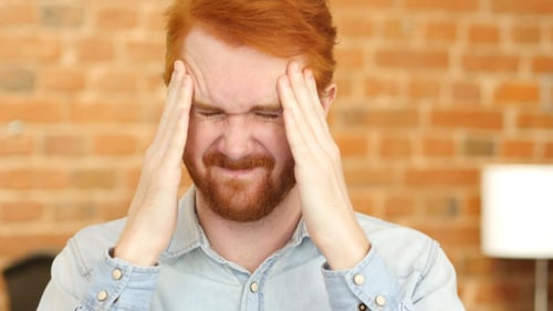 Man with Headache Holds Head in Hands