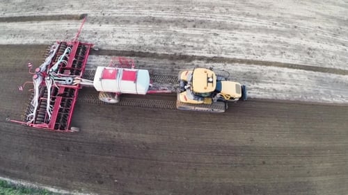 Drohnenaufnahme eines Mähdreschers, der bei Sonnenuntergang auf einem Feld arbeitet