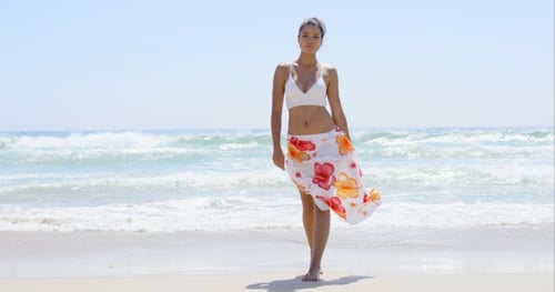 Gorgeous Young Woman Walking Along a Beach