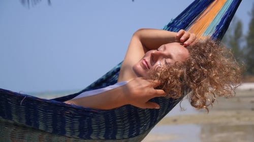 Beautiful Woman Resting In Hammock At Beach On Vacation