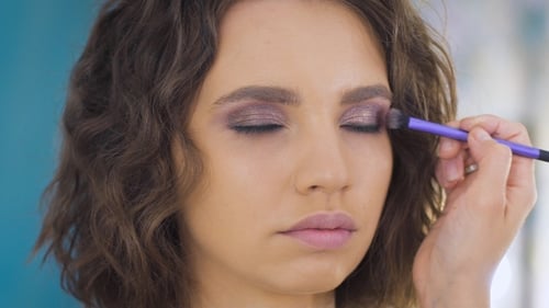 Professional Makeup Artist Applying Make Up On a Beautiful Young Face For a Photoshoot
