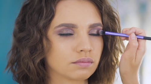 Professional Makeup Artist Applying Make Up On a Beautiful Young Face For a Photoshoot