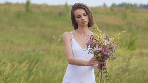 One Young Woman Standing On Green Field With Flower Bunch