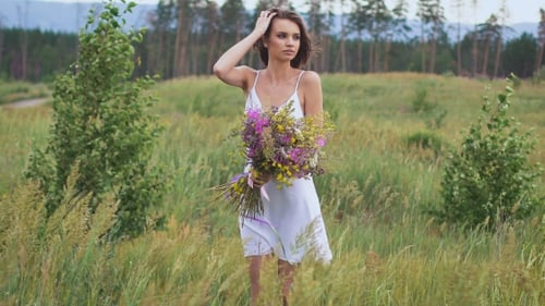 Eine junge Frau steht auf grünem Feld mit Blumenstrauß