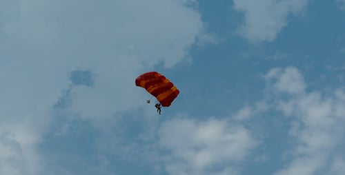 Person Skydiving with Colorful Parachute Against Cloudy Sky