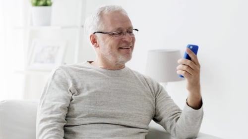Senior Man Smiling While Using Mobile Phone