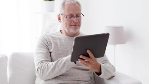 Senior Man Using Tablet on White Couch
