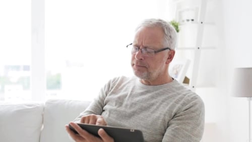 Man with Gray Hair Uses Tablet on Couch