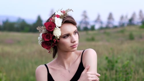 Beautiful Girl In The Black Short Dress With The Wreath On Her Head On The Green Field.