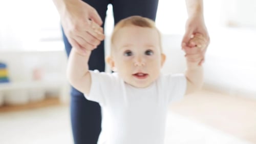 Adorable Baby Learning to Walk with Adult's Help