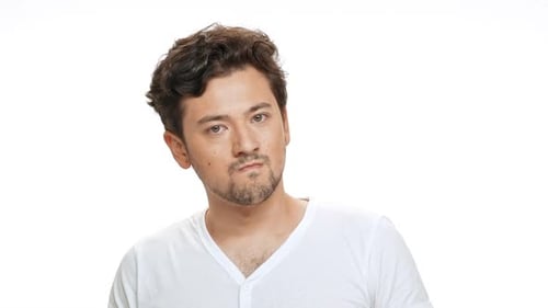 Wütender junger gutaussehender Mann schaut auf weißem Hintergrund in die Kamera