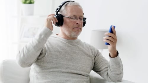 Mature Man Enjoys Music on Smartphone