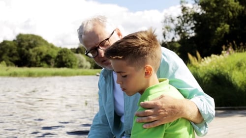 Grandfather And Grandson Sitting On River Berth 25