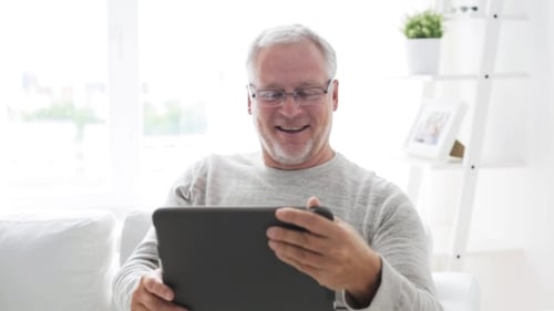 Happy Senior Man Video Calling on Tablet at Home