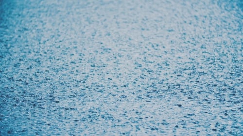 Heavy Rain Falling on Blue Surface Close Up