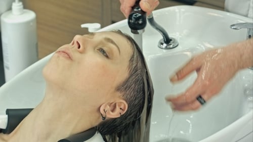Stylist Washing a Woman's Hair in a Salon