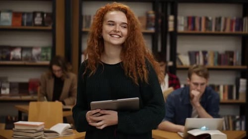 Portrait of an Attractive Long Red Haired European Girl Student Standing in High School Library