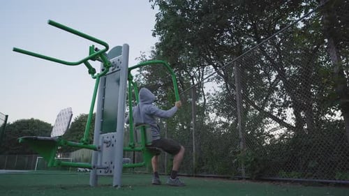 Man using a chest press machine. Evening workout in an outdoor gym. Health and fitness