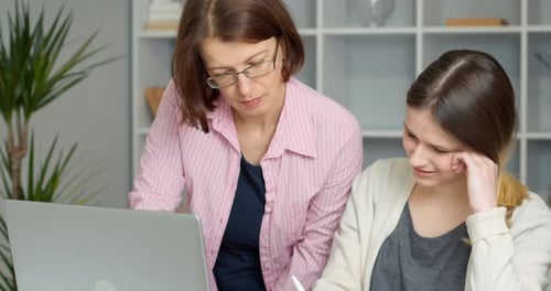Woman Helping Teenager with Laptop Indoors