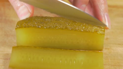 Pickle Being Sliced on a Wooden Cutting Board