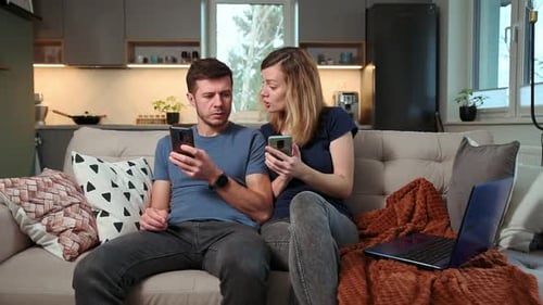 Couple Relaxing on Sofa with Mobile Phones