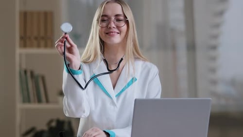 Smiling Woman Doctor Holding Up Stethoscope