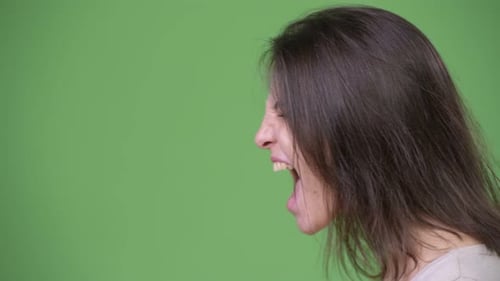 Profile View of Young Beautiful Woman Screaming Against Green Background