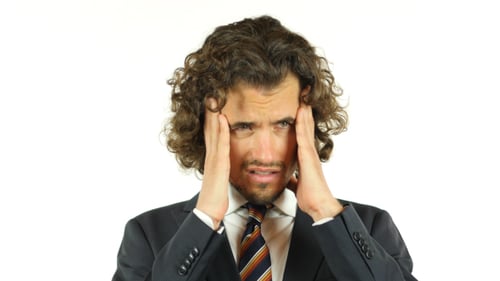 Stressed man in suit rubbing temples, forehead