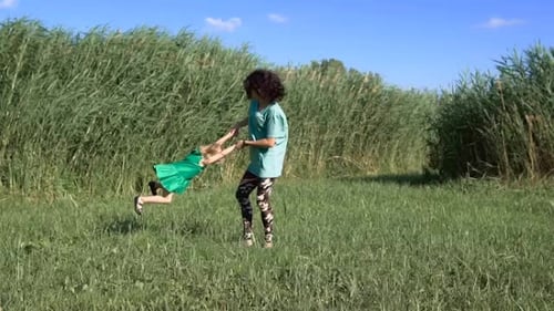 Woman and Child Spinning in Rural Grassy Field
