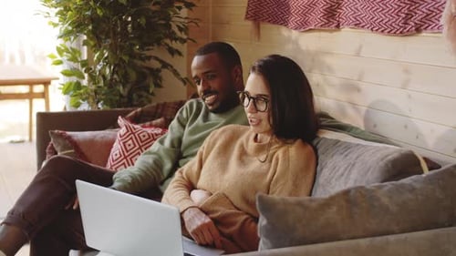 Couple Relaxing on Sofa Using Laptop
