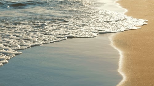 Sanfte Meereswellen rauschen am Sandstrand bei Sonnenuntergang