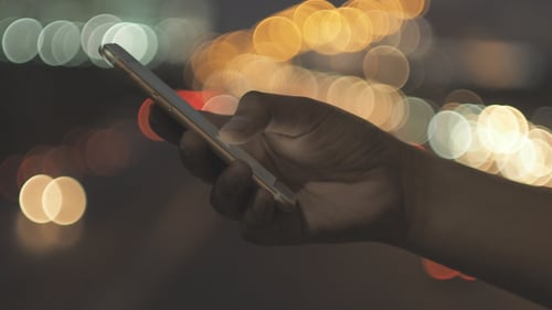 Hand Using Mobile Phone at Night with Bokeh