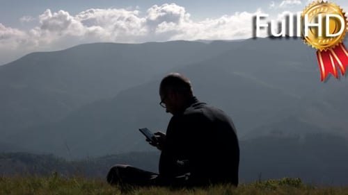 Junger Mann benutzt Handy auf einem Berggipfel