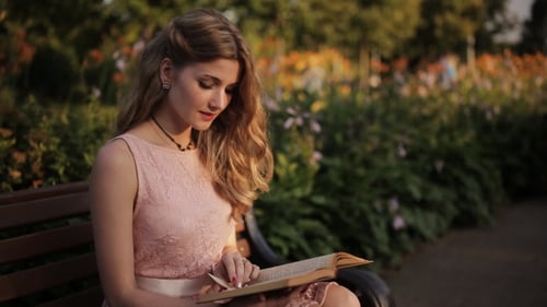 Young Woman Reading Book on Park Bench