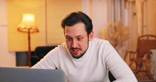 Man Celebrates Success With Laptop In Warm Home