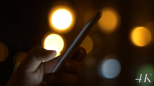 Close Up of Phone at Night with Bokeh Lights