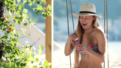 Stunning Blonde Woman Sitting On a Swing On Beach