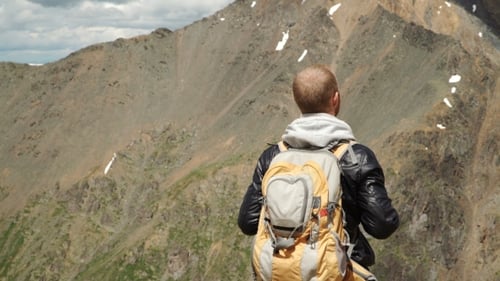 Hiker With Backpack Standing On Top Of a Mountain