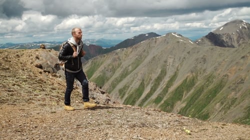 Hiker With Backpack Standing On Top Of a Mountain