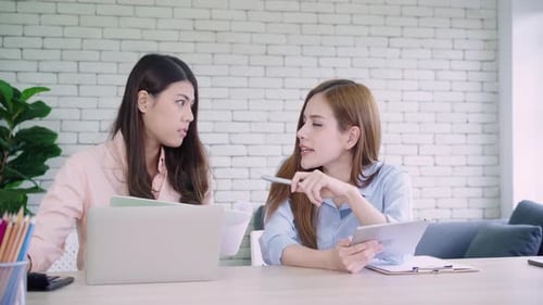 Two young Asian women working together in an office at their small busines.