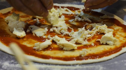 Adding Cheese to Pizza in Restaurant Kitchen
